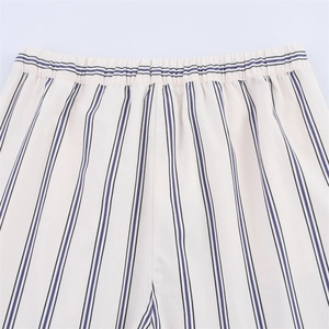 Dettaglio della vita elastica con strisce viola su pantaloni larghi beige