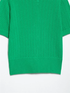 Detalle del top de punto verde que muestra texturas caladas en forma de V y acabado