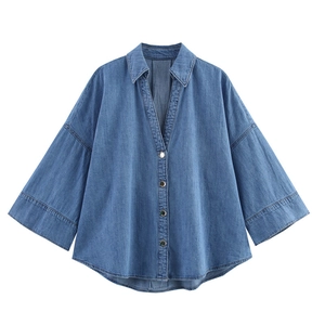 Mid-blue wash denim shirt with wide sleeves and v-neckline on white background