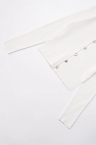 Close-up of white ribbed knit cardigan featuring decorative silver metallic buttons