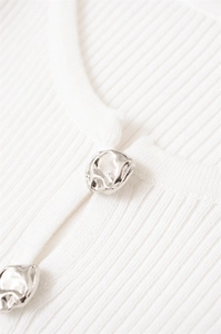 Close-up of white ribbed knit fabric with unique liquid-effect silver metal buttons