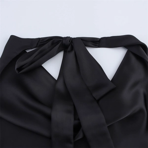 Detail eines eleganten schwarzen Satin-Neckholder-Tops mit großer Schleife am Rücken