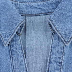 Detailed close-up of light blue denim fabric showing twill weave and orange stitching