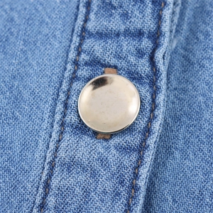 Macro shot of silver metal button and textured blue denim fabric with reinforced brown stitching