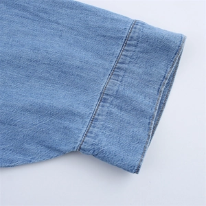 Close-up of light blue denim cuff showing twill fabric texture and neat stitching details