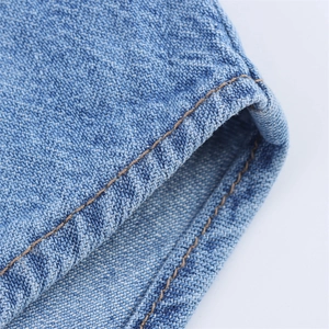 Detailed close-up of blue denim hem featuring high-quality yellow double-row stitching