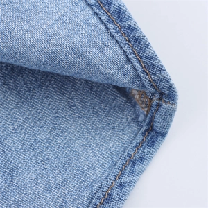 Detailed close-up of light blue denim fabric showing brown double-stitch seams and twill texture