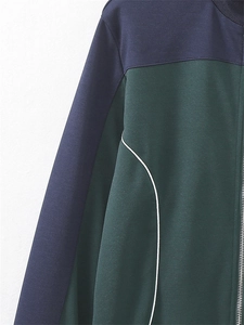 Détail de la veste bicolore avec panneaux marine et verts, zip argenté et liseré blanc