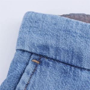 Macro view of light blue denim fabric texture and detailed waistband stitching