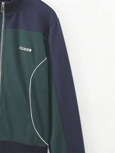 Vue détaillée de la veste zippée vert et marine avec liseré blanc et écusson