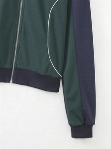 Détail de la veste de sport avec empiècements contrastés vert foncé, bleu marine et passepoil blanc