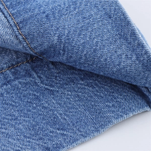 Detailed close-up of dark blue denim fabric with high-quality yellow double stitching detail