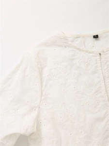Dettaglio dello scollo della camicia in cotone bianco con ricamo floreale ed etichetta taglia S