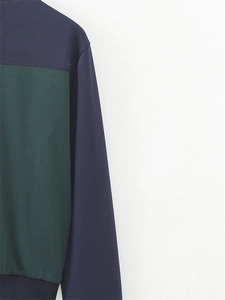 Détail de la veste bicolore montrant des panneaux bleu marine et vert foncé et ourlet