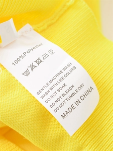 Gros plan sur la texture 100% polyester et l'étiquette de soin sur ce tricot jaune