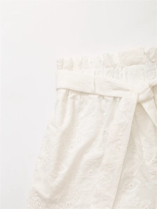 Dettaglio di pantaloncini bianchi in cotone con ricamo inglese e coulisse in vita regolabile