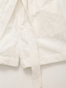 Dettaglio degli shorts bianchi in cotone con ricami floreali e inserti in pizzo Broderie Anglaise