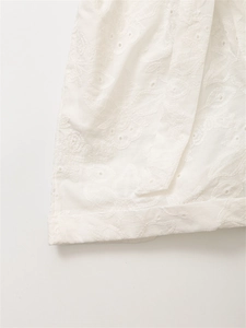 Dettaglio di camicia in cotone bianco con ricamo floreale traforato e cuciture rifinite