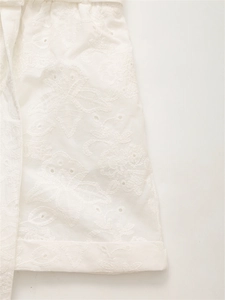 Dettaglio del tessuto Broderie Anglaise bianco con ricamo floreale e occhielli traforati