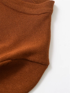 Détail du col rond et de la texture en maille fine sur un haut en tricot couleur caramel