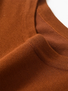 Détail de la texture douce du pull en maille marron et du col rond bien fini