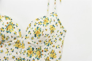Close-up of heart neckline with yellow floral print and thin straps on poplin dress