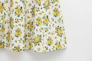 Detail of floral print poplin fabric featuring yellow flowers and blue leaves on white