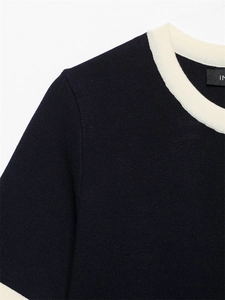 Detailed view of navy blue knit top featuring contrasting cream ribbed crew neck and trim