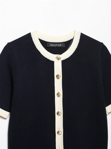 Detailed macro view of navy knit cardigan with cream piping and gold relief buttons