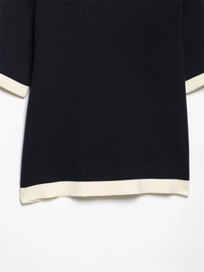 Detail shot of navy knit fabric with white contrast trim on sleeve and hemline