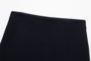 Close-up of black knit fabric texture and minimalist waist design on a mini skirt