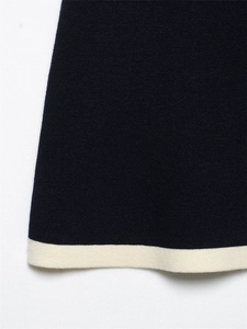 Close-up of navy blue knit hem with ivory contrast trim and high-density texture