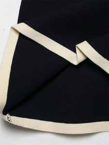 Detailed close-up of navy knit cardigan with cream contrast ribbed trim and fine texture