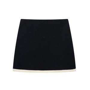 Detail of A-line knit mini skirt featuring a contrast cream border on black fabric