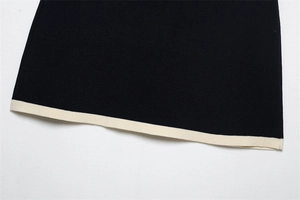 Close-up of the knitted hem featuring elegant contrast cream trim on a black fabric