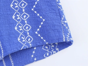 Detaillierte Makroansicht weißer geometrischer Stickerei auf royalblauem Baumwollstoff