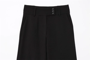 Close-up of high-waisted black trousers showing three decorative buttons and pockets