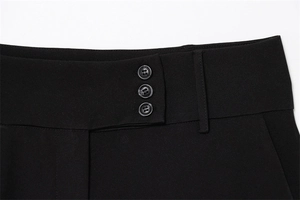 Detailed macro view of high-waist black trousers featuring a unique three-button waist design