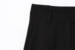 Detail of high waist trousers showing belt loops and high-quality tailoring on black fabric