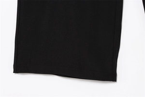 Detail shot of black wide-leg trousers showing neat stitching and fine woven fabric texture