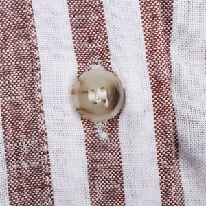 Détail d'une chemise rayée en lin montrant le tissu respirant et un bouton marbré
