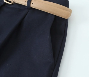 Dettaglio dei pantaloncini blu navy con trama in twill e sottile cintura in pelle kaki