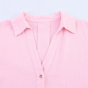 Détail d'une chemise en lin rose clair avec col élégant et bouton en résine ambrée