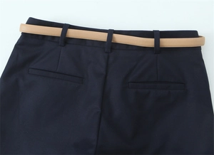 Dettaglio dei pantaloncini blu scuro con passanti e una sottile cintura in pelle marrone