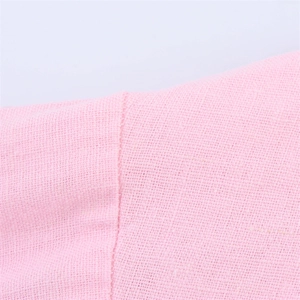 Gros plan détaillé sur la texture du lin rose et les coutures précises d'une chemise