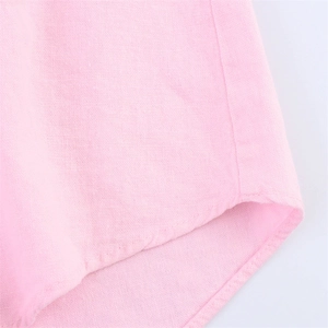 Détail macro de l'ourlet incurvé et des coutures fines sur une chemise rose en lin