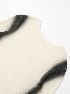 Détail du pull en maille blanc cassé montrant la texture et l'effet dégradé noir