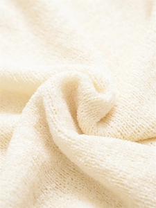 Détail macro du tricot crème doux montrant la texture bouclée respirante et les plis