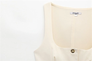 Detail of square neckline with ZEDeRI brand label and texture button on cream top