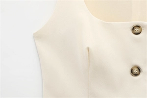 Detail of cream sleeveless top featuring tortoiseshell buttons and structured tailoring
